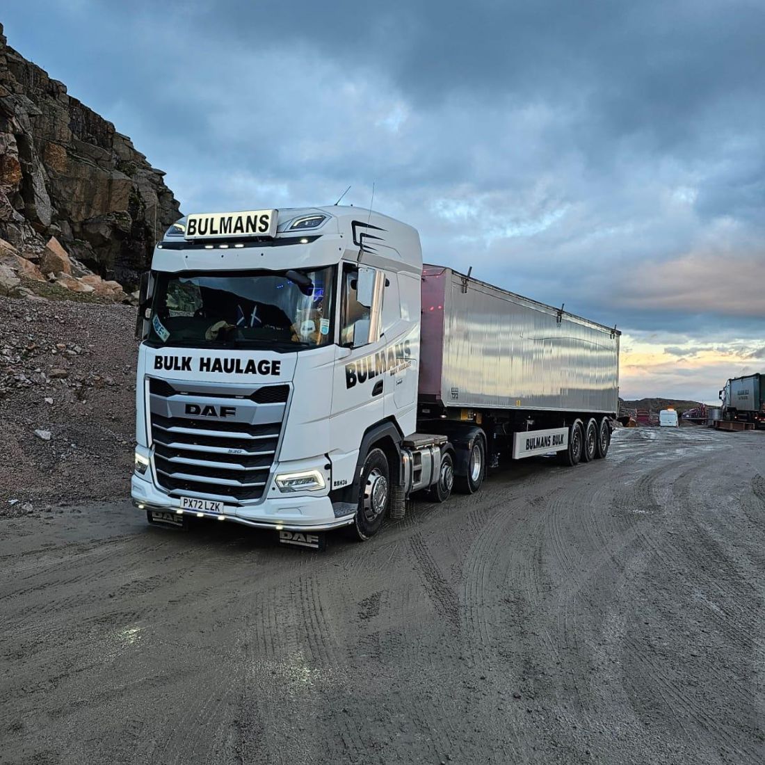 A Bulmans Bulk Haulage white DAF truck, parked in a quarry with a dramatic cloudy sky overhead.