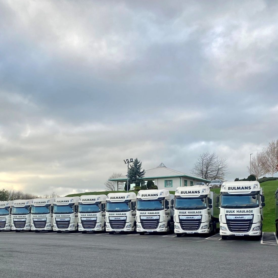 A lineup of Bulmans Bulk Haulage vehicles, showcasing a fleet of white DAF trucks with the company logo, ready for nationwide transport services.