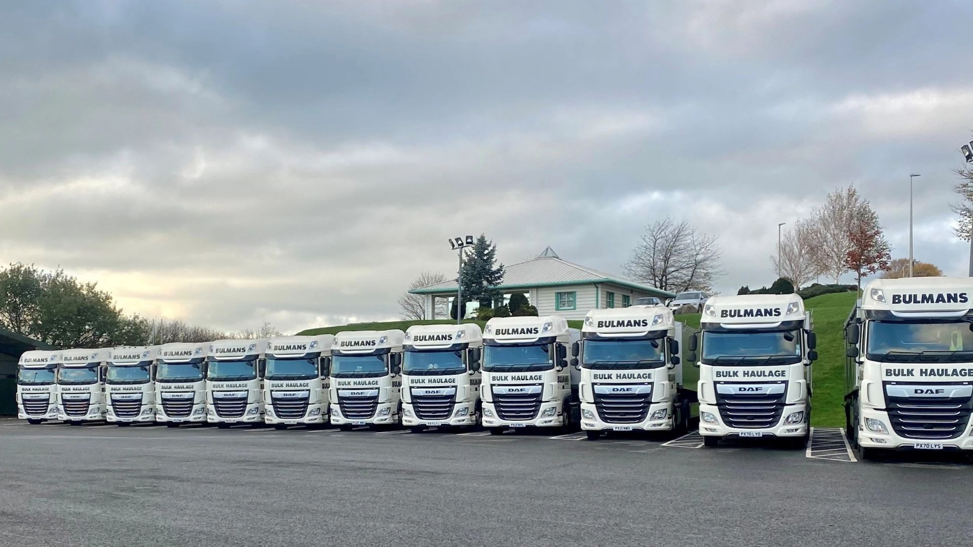 A lineup of Bulmans Bulk Haulage vehicles, showcasing a fleet of white DAF trucks with the company logo, ready for nationwide transport services.